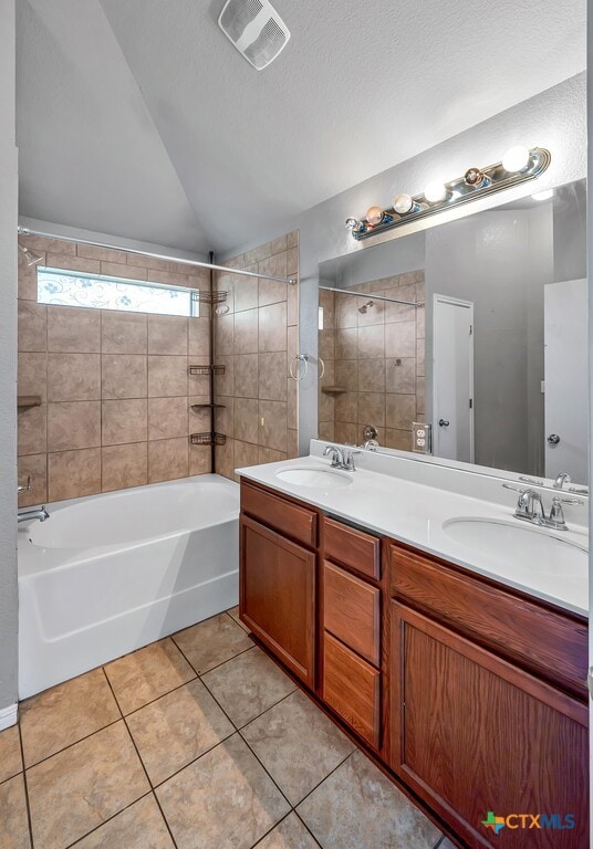 bathroom featuring vanity, a textured ceiling, tiled shower / bath combo, tile patterned flooring, and lofted ceiling