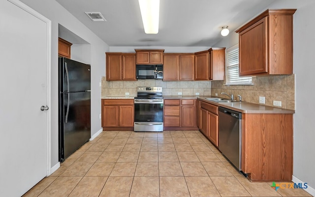 kitchen featuring light tile patterned floors, sink, black appliances, and tasteful backsplash