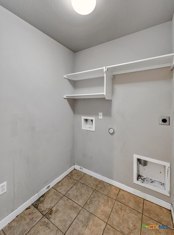 clothes washing area with washer hookup, a textured ceiling, electric dryer hookup, gas dryer hookup, and tile patterned floors