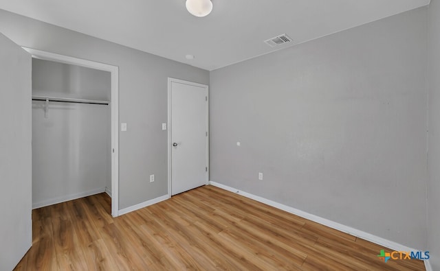 unfurnished bedroom with hardwood / wood-style flooring and a closet