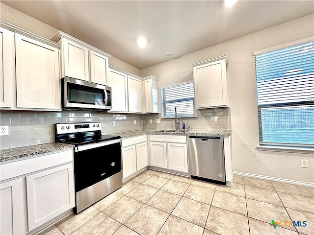 kitchen with white cabinets, light stone countertops, sink, and stainless steel appliances