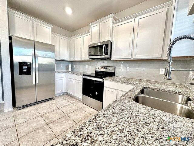 kitchen featuring sink, white cabinetry, light tile patterned floors, and stainless steel appliances