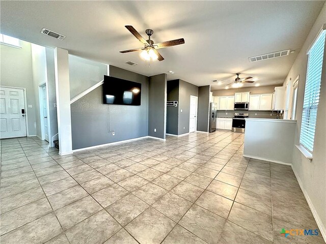 kitchen featuring light tile patterned floors, appliances with stainless steel finishes, white cabinets, and ceiling fan