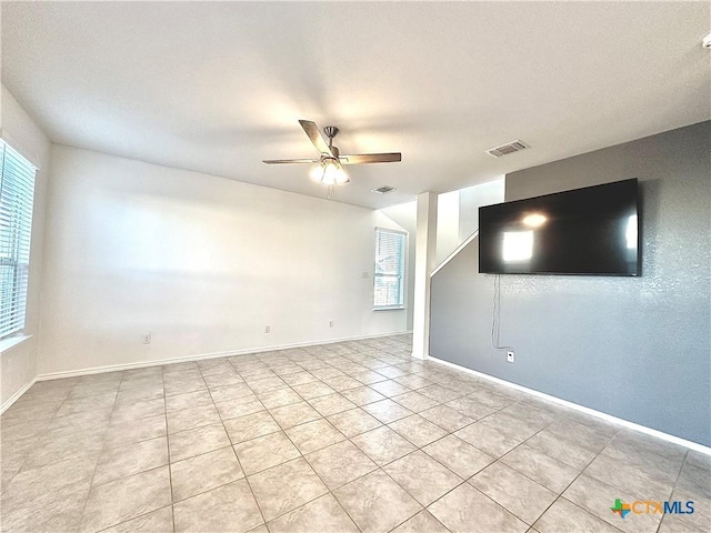 empty room featuring ceiling fan, light tile patterned flooring, and plenty of natural light