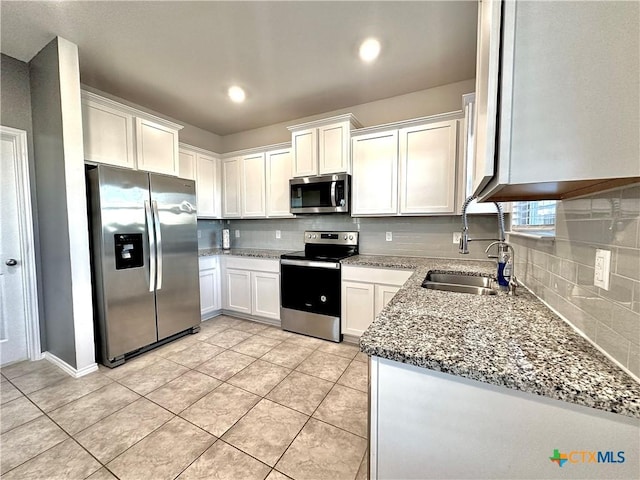 kitchen featuring appliances with stainless steel finishes, white cabinetry, backsplash, light tile patterned flooring, and light stone counters