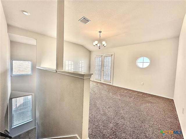 unfurnished room with vaulted ceiling, a chandelier, and dark colored carpet