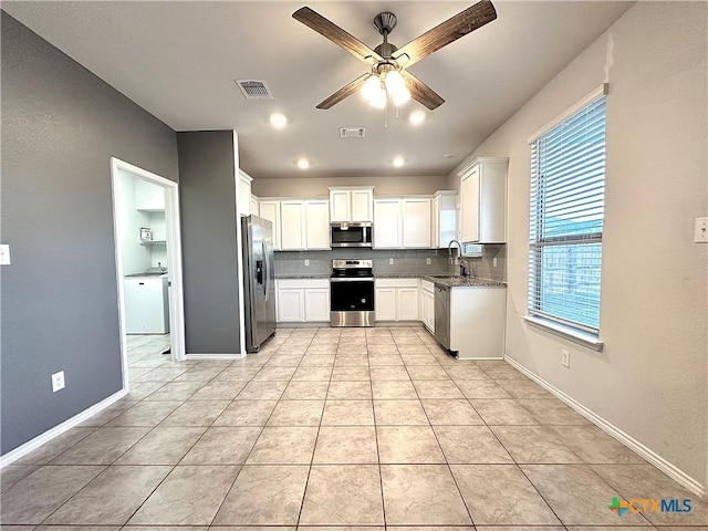 kitchen featuring white cabinetry, stainless steel appliances, decorative backsplash, sink, and ceiling fan