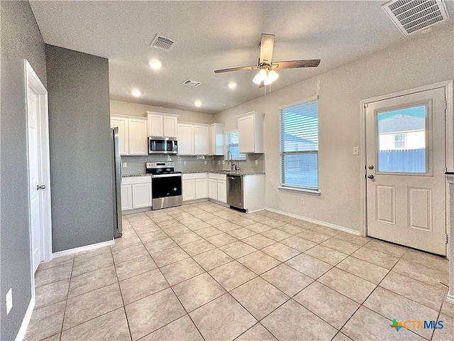 kitchen with appliances with stainless steel finishes, white cabinetry, tasteful backsplash, ceiling fan, and light tile patterned floors