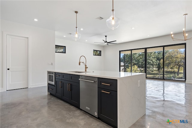 kitchen featuring sink, an island with sink, decorative light fixtures, ceiling fan with notable chandelier, and appliances with stainless steel finishes