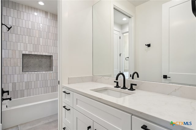 bathroom featuring tile patterned flooring, tiled shower / bath combo, and vanity