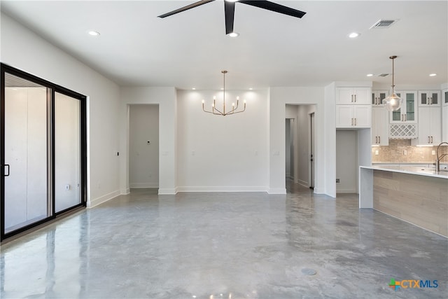 interior space featuring concrete flooring, ceiling fan with notable chandelier, and sink