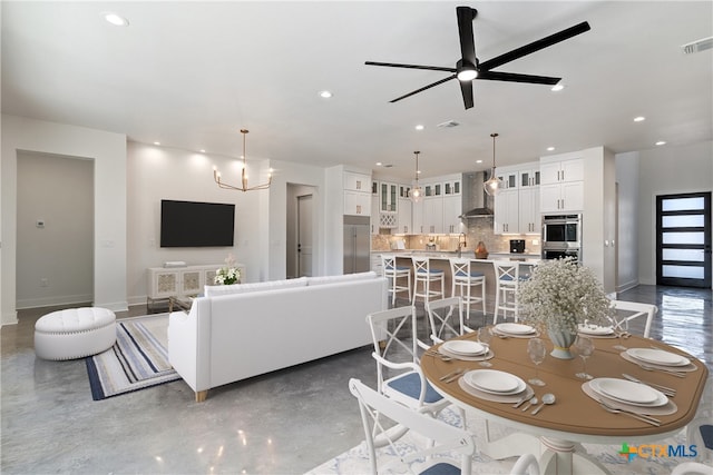 dining area with ceiling fan with notable chandelier and sink