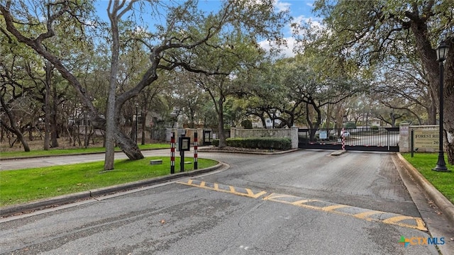 view of road with a gate, curbs, a gated entry, and street lights