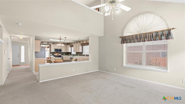 kitchen featuring stainless steel appliances, light countertops, light colored carpet, and baseboards