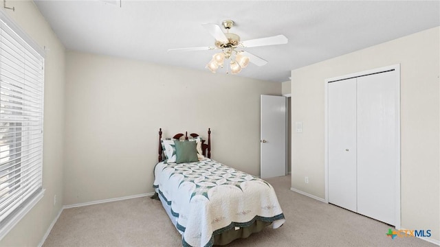 bedroom with light carpet, a closet, a ceiling fan, and baseboards