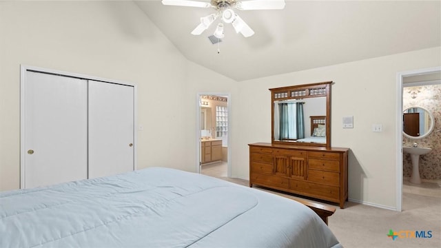 bedroom with a closet, light carpet, ceiling fan, ensuite bath, and baseboards