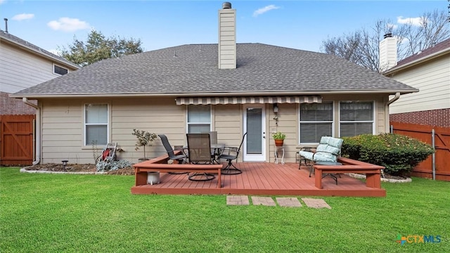 back of house featuring roof with shingles, fence, and a yard