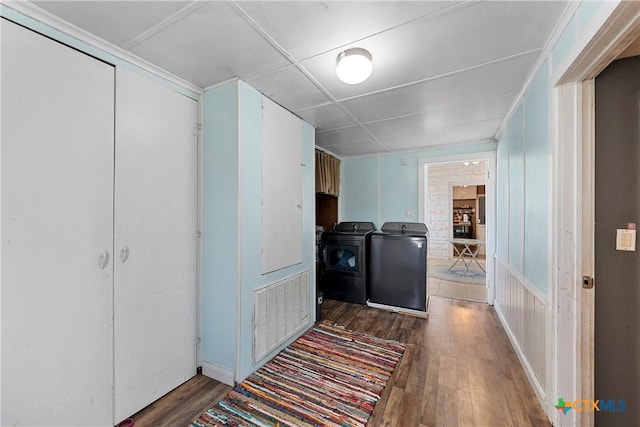 hall featuring wood finished floors, visible vents, and independent washer and dryer