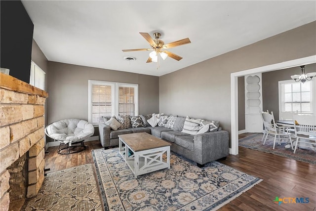 living area with visible vents, ceiling fan with notable chandelier, and wood finished floors