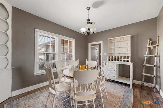 dining space with a chandelier, baseboards, and wood finished floors