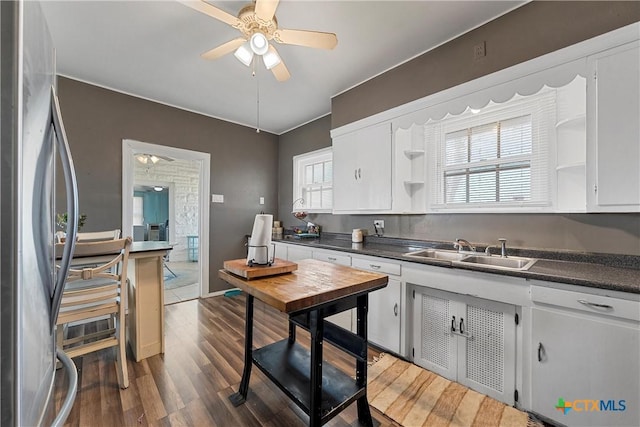 kitchen featuring open shelves, dark countertops, freestanding refrigerator, and a sink