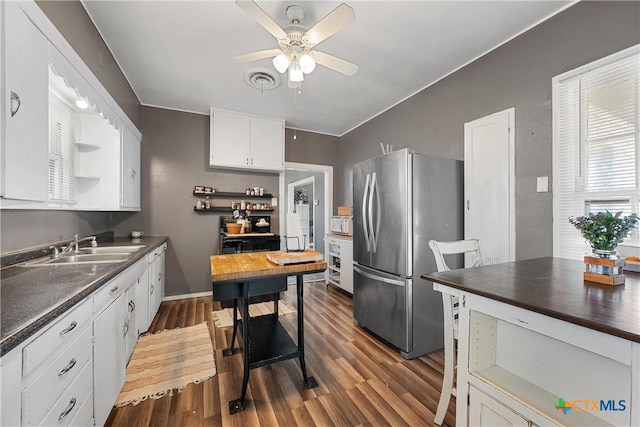 kitchen featuring dark countertops, open shelves, freestanding refrigerator, white cabinets, and a sink