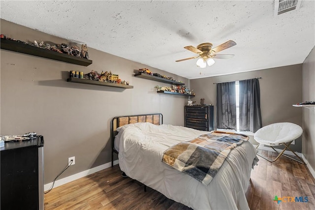 bedroom with visible vents, baseboards, and wood finished floors