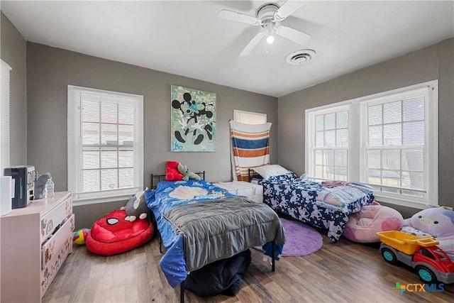 bedroom featuring ceiling fan, visible vents, and wood finished floors