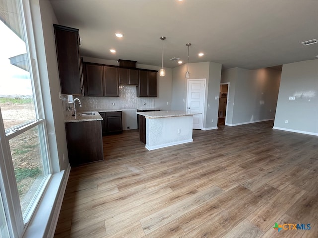 kitchen with a kitchen island, light stone countertops, wood-type flooring, and a healthy amount of sunlight