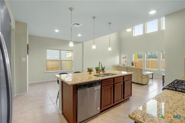 kitchen featuring pendant lighting, sink, an island with sink, stainless steel appliances, and light tile patterned floors