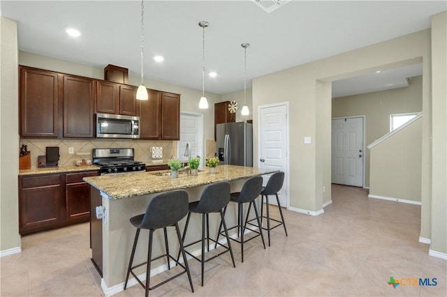 kitchen with a breakfast bar, sink, stainless steel appliances, and a center island with sink