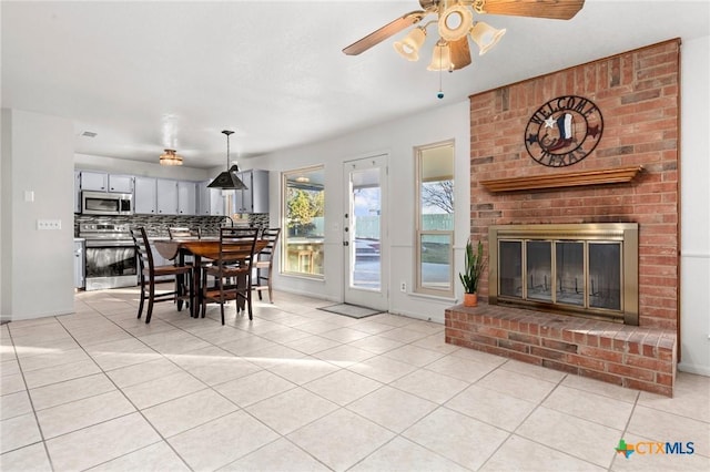 tiled dining room with ceiling fan and a fireplace