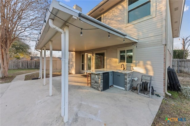 rear view of property with area for grilling, sink, and a patio area