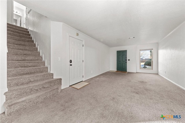 unfurnished living room with ornamental molding and carpet floors