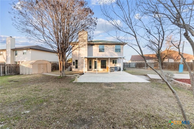 rear view of property featuring a yard, a shed, and a patio