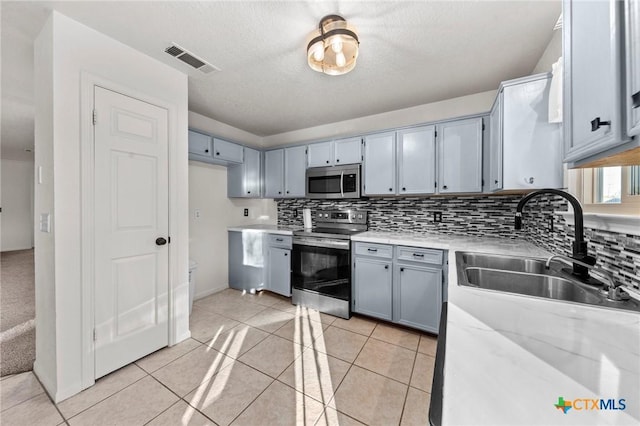 kitchen featuring light stone countertops, light tile patterned flooring, appliances with stainless steel finishes, and sink