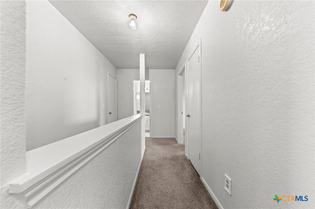 hall with carpet floors and a textured ceiling