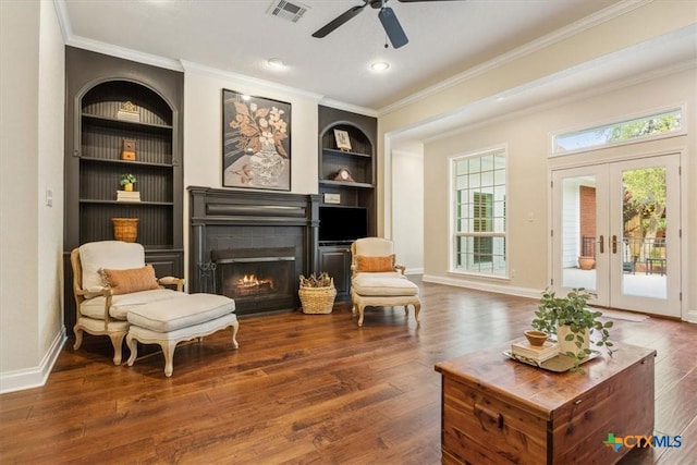 11421 Somerville Dr, Temple, TX 76502 - living area featuring built in features, a warm lit fireplace, wood finished floors, ornamental molding, and a ceiling fan