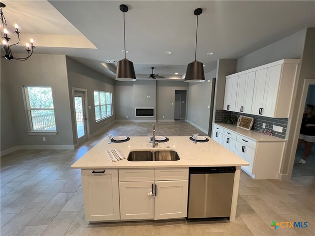 kitchen with white cabinets, dishwasher, open floor plan, a sink, and backsplash