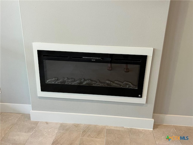 interior details with baseboards and a glass covered fireplace