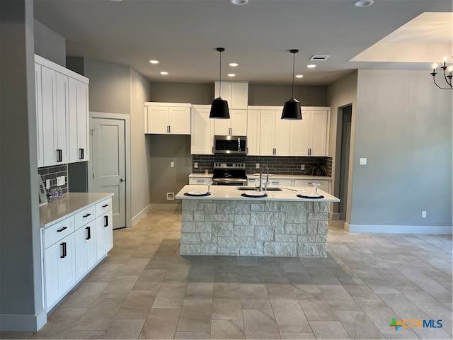 kitchen featuring visible vents, white cabinets, a kitchen island with sink, stainless steel appliances, and a sink