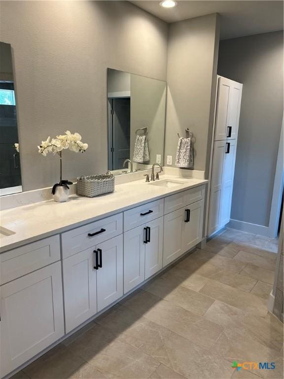 bathroom with double vanity, a sink, and baseboards