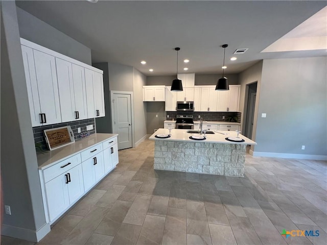 123 S Calvin Barrett, Blanco, TX 78606 - kitchen with stainless steel appliances, backsplash, an island with sink, white cabinetry, and recessed lighting