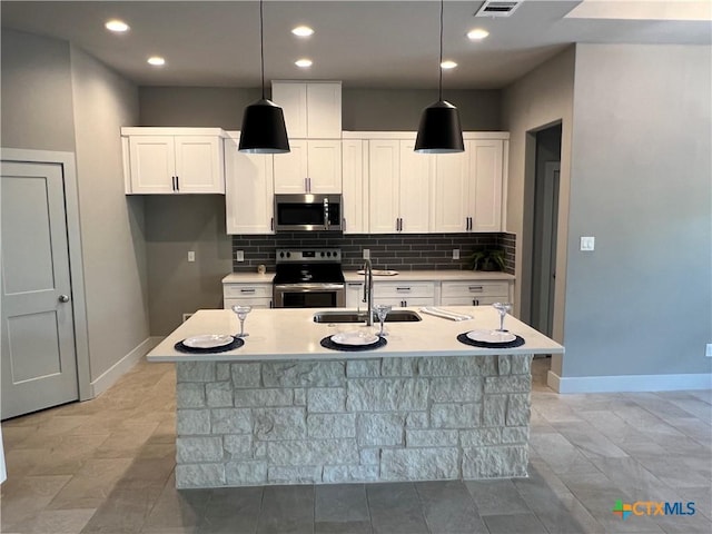 123 S Calvin Barrett, Blanco, TX 78606 - kitchen featuring appliances with stainless steel finishes, white cabinetry, tasteful backsplash, light countertops, and an island with sink