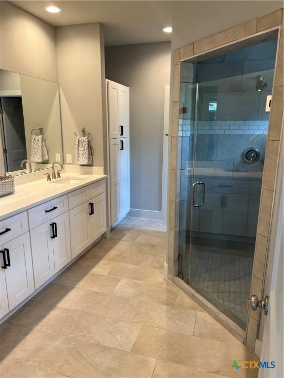 full bath featuring a stall shower, vanity, and baseboards