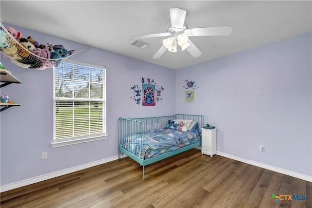 bedroom featuring wood finished floors, visible vents, a ceiling fan, and baseboards