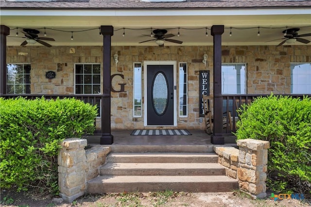 property entrance with a ceiling fan, stone siding, and covered porch