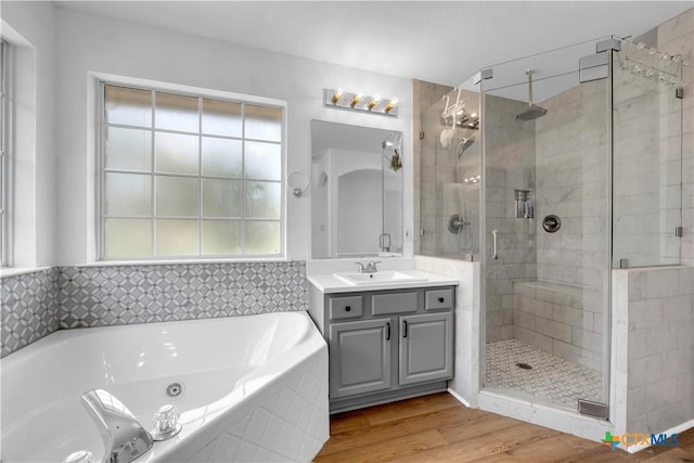 full bath featuring a shower stall, vanity, a tub with jets, and wood finished floors
