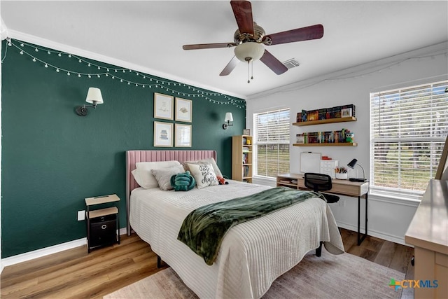 bedroom with visible vents, wood finished floors, ceiling fan, and multiple windows
