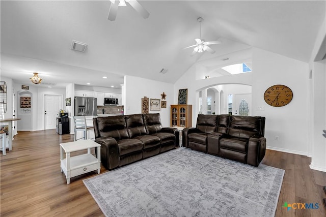 living area with arched walkways, visible vents, a ceiling fan, and high vaulted ceiling